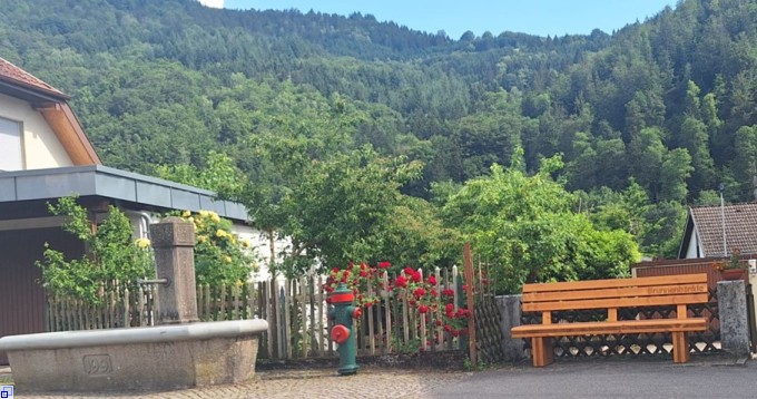 Sitzbank aus Holz neben dem Dorfbrunnen
